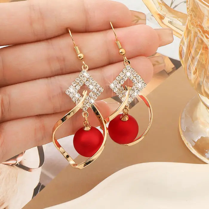 Gold hook earrings adorned with red beads and sparkling crystals for chic women’s jewelry styles.