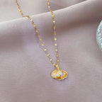 gold seashell necklace featuring open shell pendant revealing pearl inside on soft fabric background