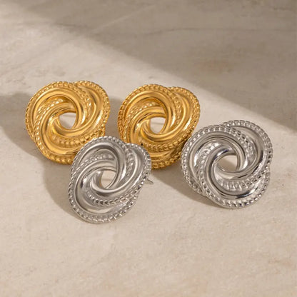 Gold and silver twisted knot earrings set on a beige surface, perfect for chic and modern accessorizing.