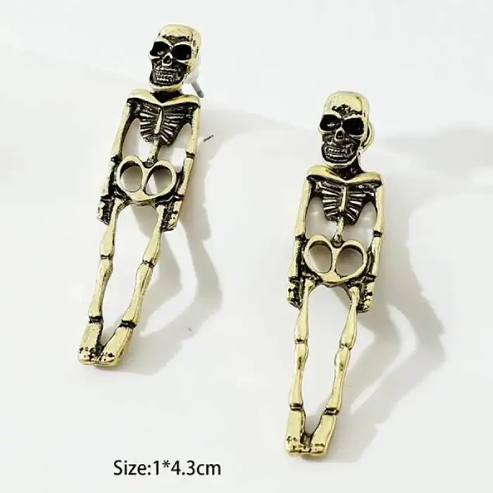 Gold-tone skeleton earrings with full body bone structure design placed on white background.