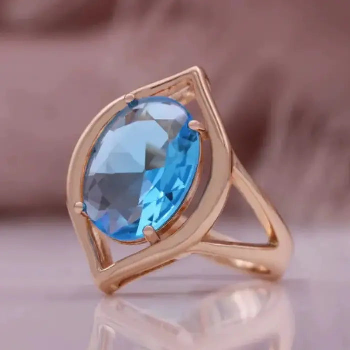 gold teardrop birthstone ring design shown with a bold blue oval gemstone in a modern open-frame gold setting for elegant styling