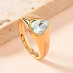 gold teardrop birthstone ring featuring a clear crystal gemstone set in polished gold, displayed on soft neutral background for detail