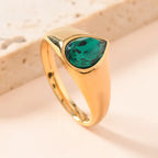 gold teardrop birthstone ring with a vivid emerald green gemstone set in polished gold, shown in a clean modern product layout