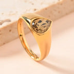 gold teardrop birthstone ring featuring a smoky quartz-style gem in a sleek gold band displayed in a warm, minimalist setting
