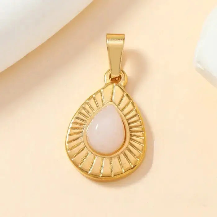 Gold teardrop pendant with pink opal gemstone and radiant textured design, perfect for statement jewelry.