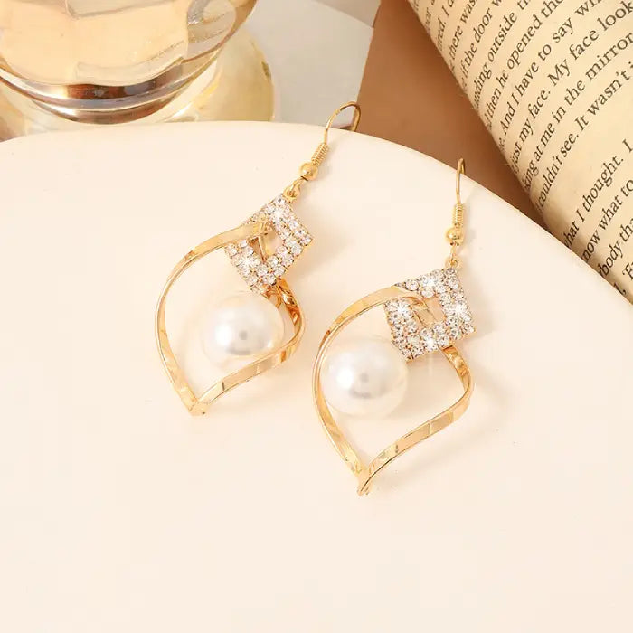 Elegant gold dangle earrings with white beads and crystal accents for women’s refined accessories.