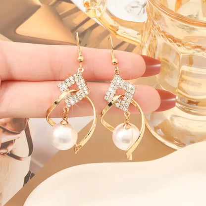 Glamorous gold drop earrings featuring white beads and sparkling crystals for sophisticated looks.