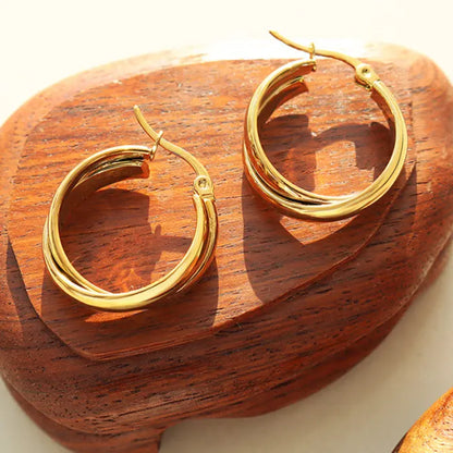 Shiny golden hoop earrings displayed on rustic wooden surface with natural lighting