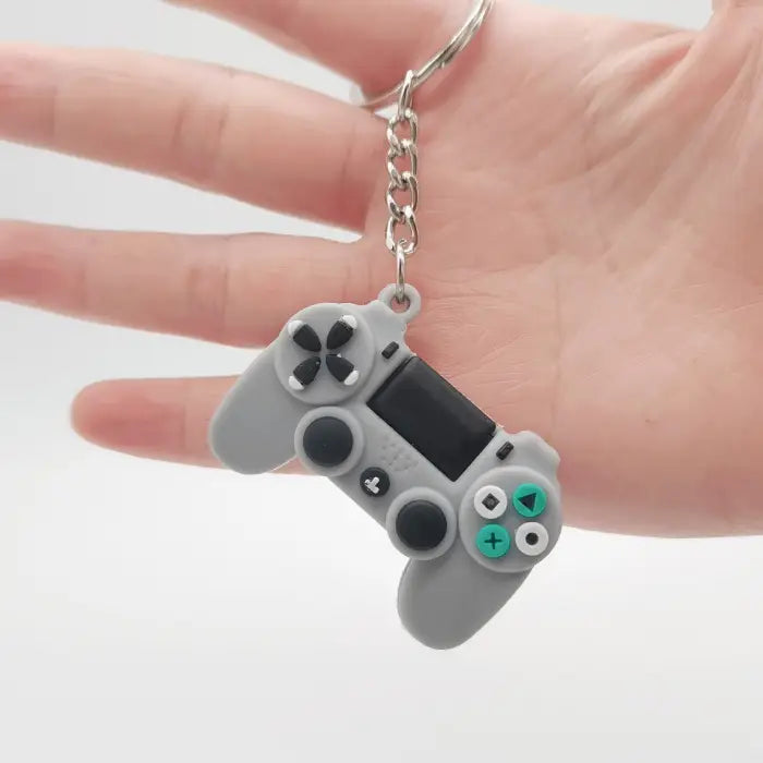 A gray game controller keychain held in hand, perfect for gaming-related merchandise or accessories.