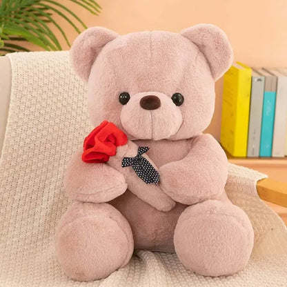 Cute gray teddy bear with a red rose and black polka dot bow on couch.