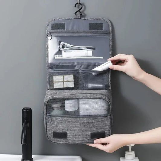 Gray hanging toiletry bag with multiple compartments, displayed open and closed on white background