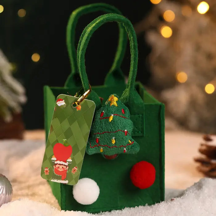 Green Christmas gift bag featuring a tree ornament, pom-poms, and a festive tag.