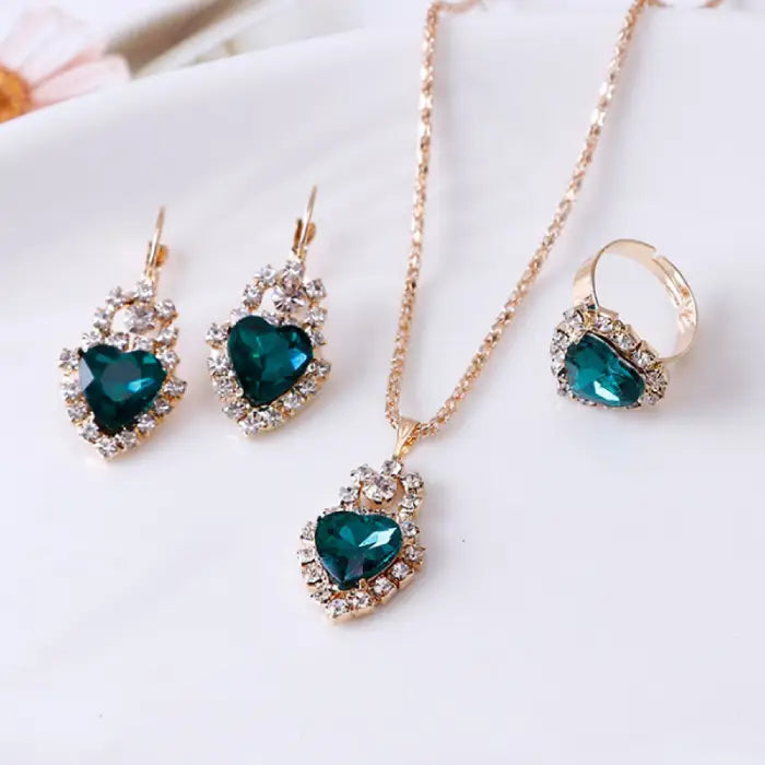 Elegant green gemstone heart jewelry set with matching necklace, earrings, and ring in a gold finish.