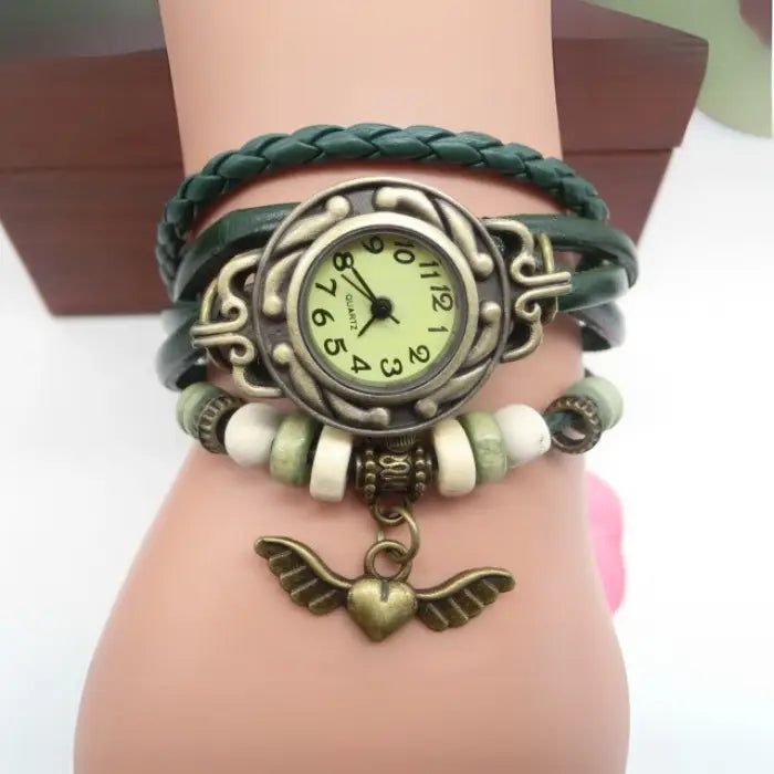 Green leather wrap bracelet watch featuring decorative beads and heart charm for a bohemian fashion vibe.