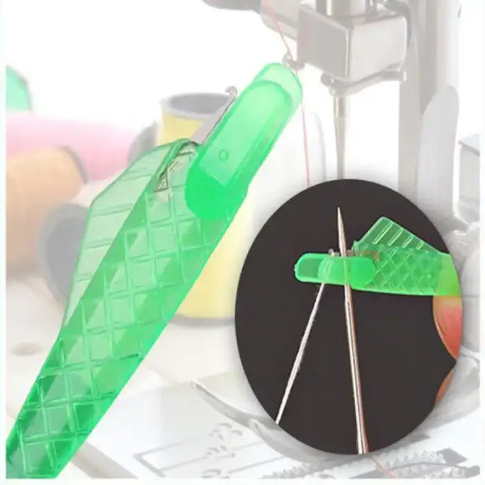 Green needle threader aligning with metal needle tip for threading, sewing tools blurred in background