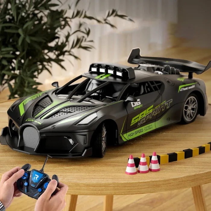 Green remote control racing car with a sleek design on a wooden table, accompanied by a controller and miniature cones.