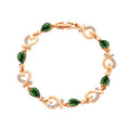 Gold plated bracelet with green teardrop gemstones and heart designs, sparkling with a luxurious aesthetic.
