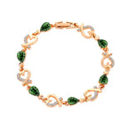 Gold plated bracelet with green teardrop gemstones and heart designs, sparkling with a luxurious aesthetic.