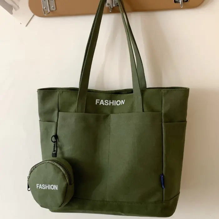 Green tote bag with mini pouch labeled "Fashion," hanging neatly on a modern wall hook.