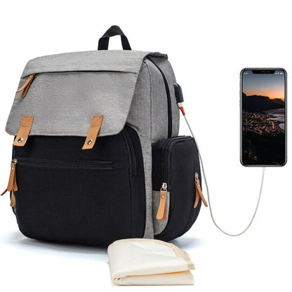 Modern grey diaper backpack with leather accents, USB charging port and baby essentials storage for outdoor adventures