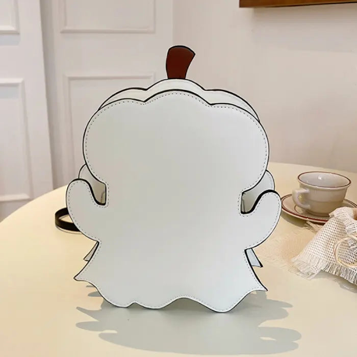 Halloween crossbody bag back view showing plain white ghost-shaped design on tabletop.