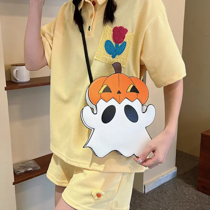 Halloween crossbody ghost and pumpkin bag styled with yellow outfit indoors.