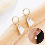 Halloween earrings with cute white ghost charms and gold hoops shown on display and worn on ear.