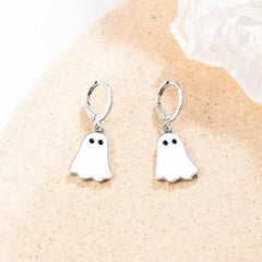 Silver hoop Halloween earrings with white ghost charms displayed on neutral textured surface.