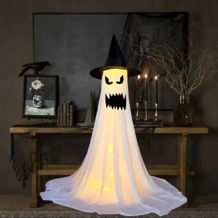 Halloween Ghost Yard Decor ghost with sharp black teeth and witch hat glowing in spooky room.