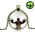 Halloween Glow necklace with creepy silhouette hands design in antique bronze horror pendant.