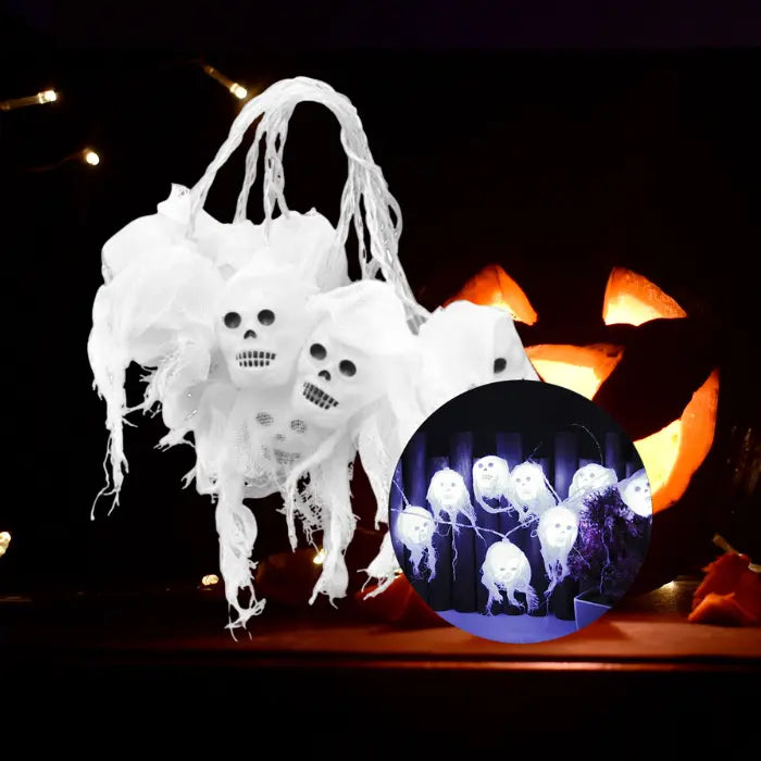 Halloween lights with glowing white ghost skull string hanging on dark fence.