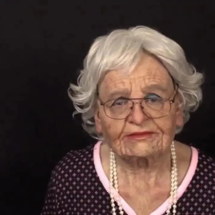 Halloween Mask of elderly woman with white curly wig, glasses, and pink dress with pearls