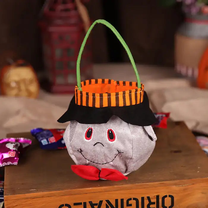 Halloween pumpkin candy bag shaped like smiling ghost with red bow and striped handle