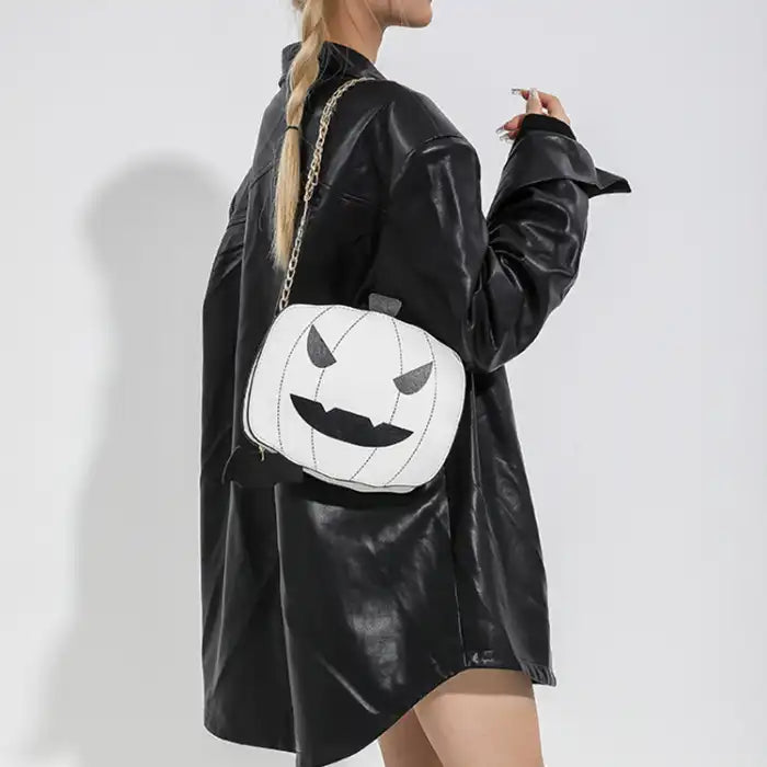 Halloween Pumpkin Head bag in white with black face and gold chain worn with black faux leather outfit