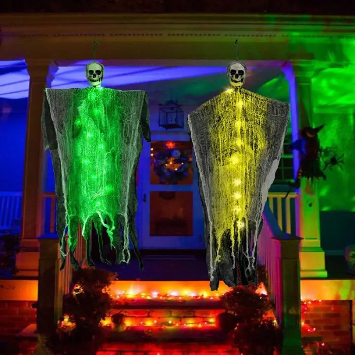 Pair of floating halloween skeleton ghosts with black draped fabric hanging outdoors in trees.