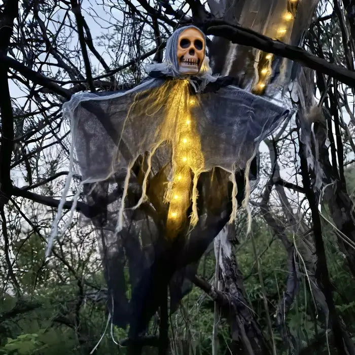 Halloween skeleton ghost with glowing body hanging from tree in outdoor spooky scene at dusk.