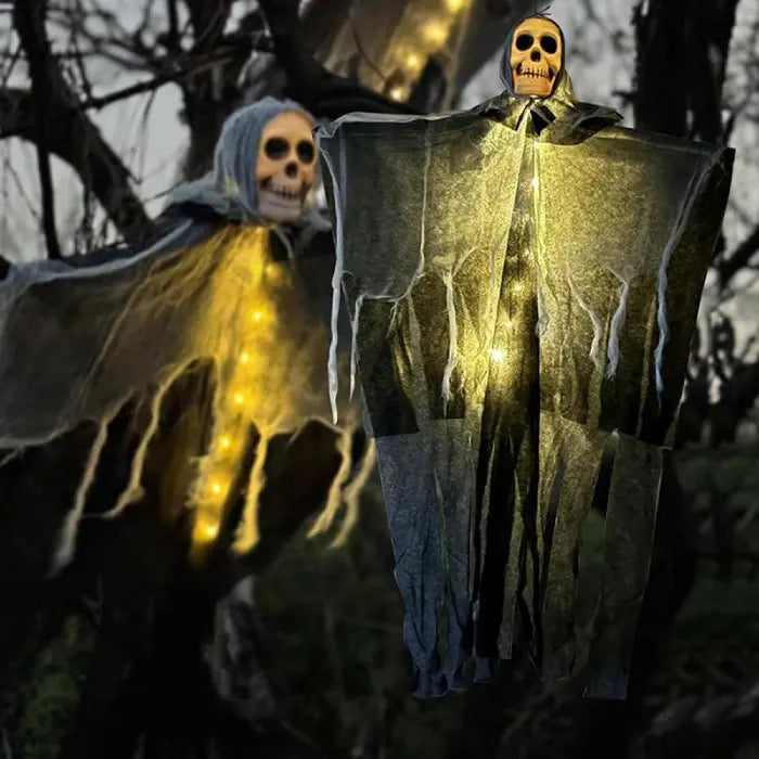 Pair of halloween skeleton ghosts glowing with yellow lights hanging outdoors on trees in dark spooky forest.