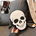 Close-up of Halloween Skull Bag with white skull graphic on black faux leather set on couch.