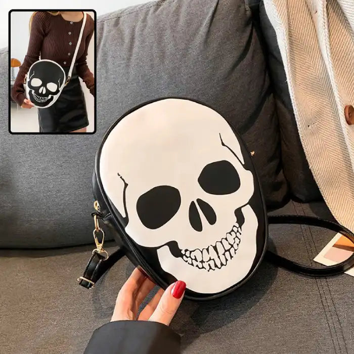 Close-up of Halloween Skull Bag with white skull graphic on black faux leather set on couch.