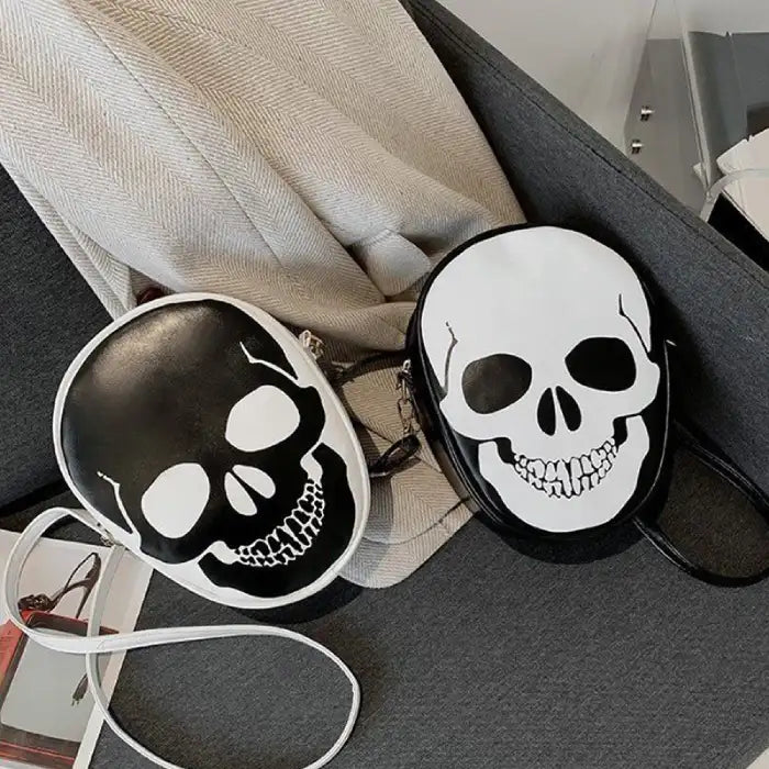 Two Halloween Skull Bags in black and white displayed together on a grey sofa with contrast straps.