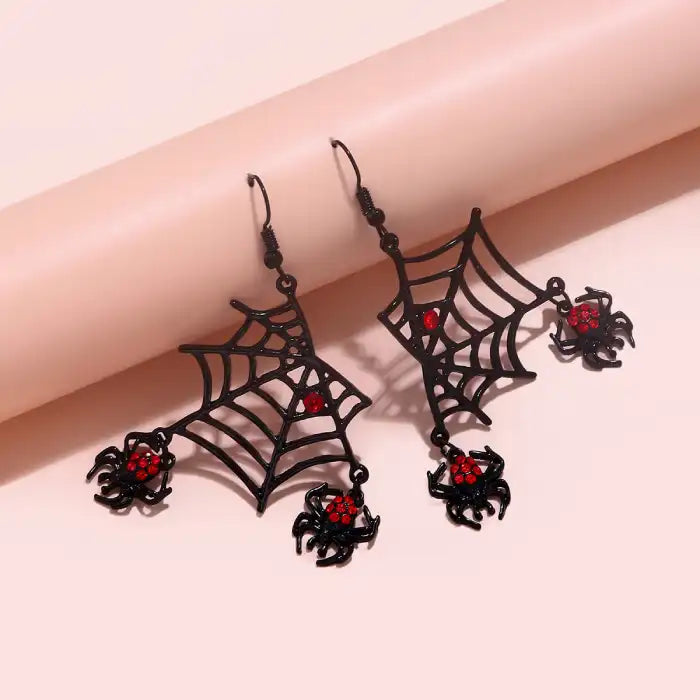 Halloween spider web earrings with red gem spiders in black metal design on pink background