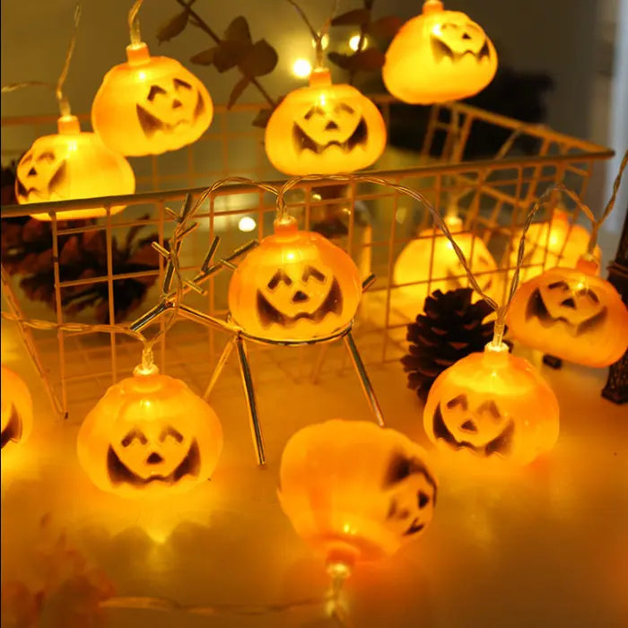 Halloween string lights with bright orange pumpkin face bulbs in a wire basket display