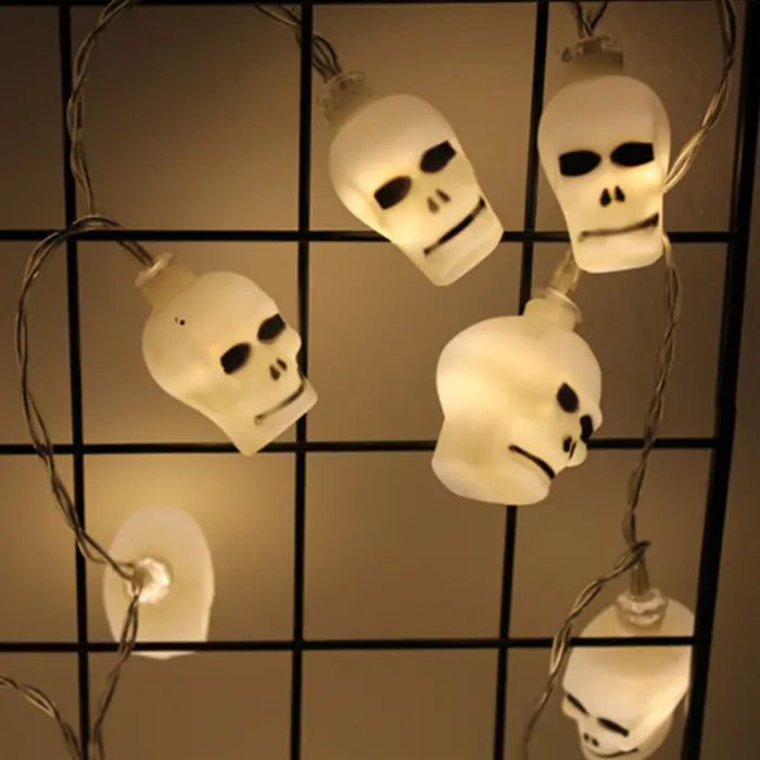 Halloween string lights with illuminated skull-shaped bulbs arranged on a black wire grid