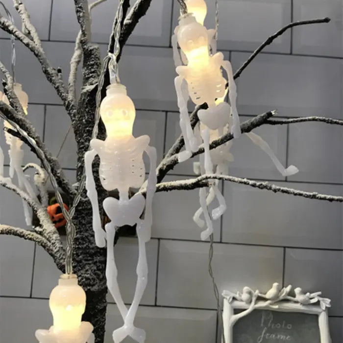 Halloween string lights with glowing white skeletons hanging from a decorative indoor tree