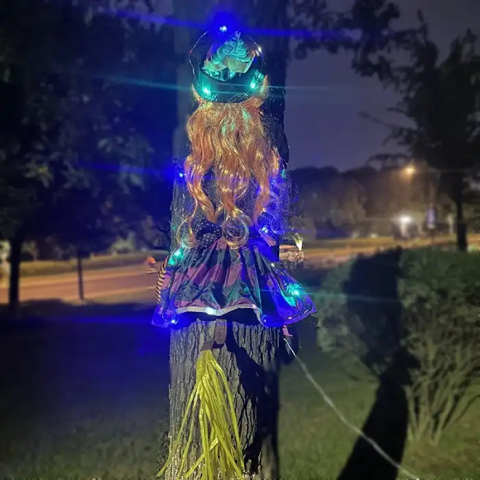 Halloween Witch Outdoor Courtyard Pendant glowing with colorful lights wrapped around tree at night.