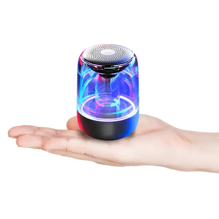 Open palm holding small wireless speaker with glowing blue and pink lights and transparent body