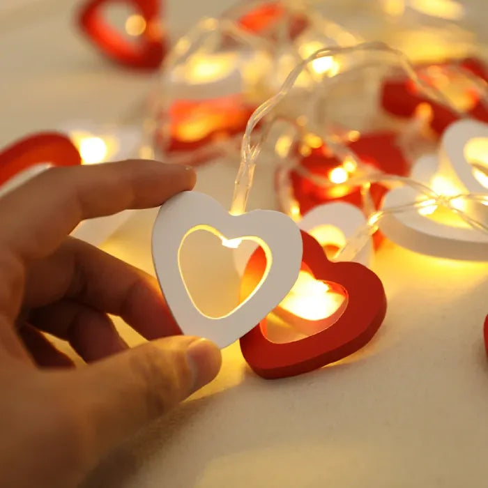 A hand holding a white heart light, demonstrating its delicate glow.