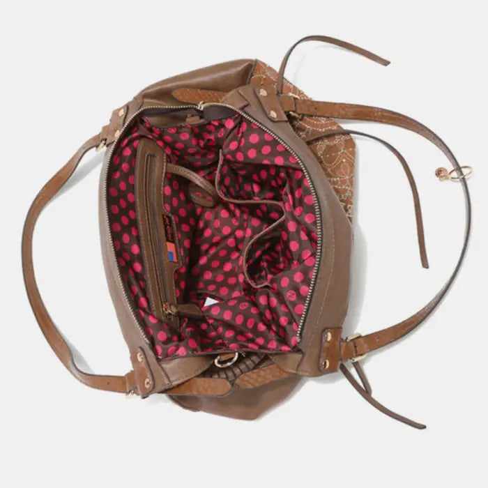 Top view of handbag revealing spacious interior with pink polka dot design and multiple compartments.