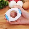 compact egg opener with blue accents held in hand against a wooden kitchen counter