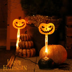 Halloween-themed decorations with jack-o'-lantern faces and stacked pumpkins on a dark background.